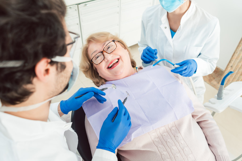 Team of dentists talking to senior patient in their surgery explaining the treatment