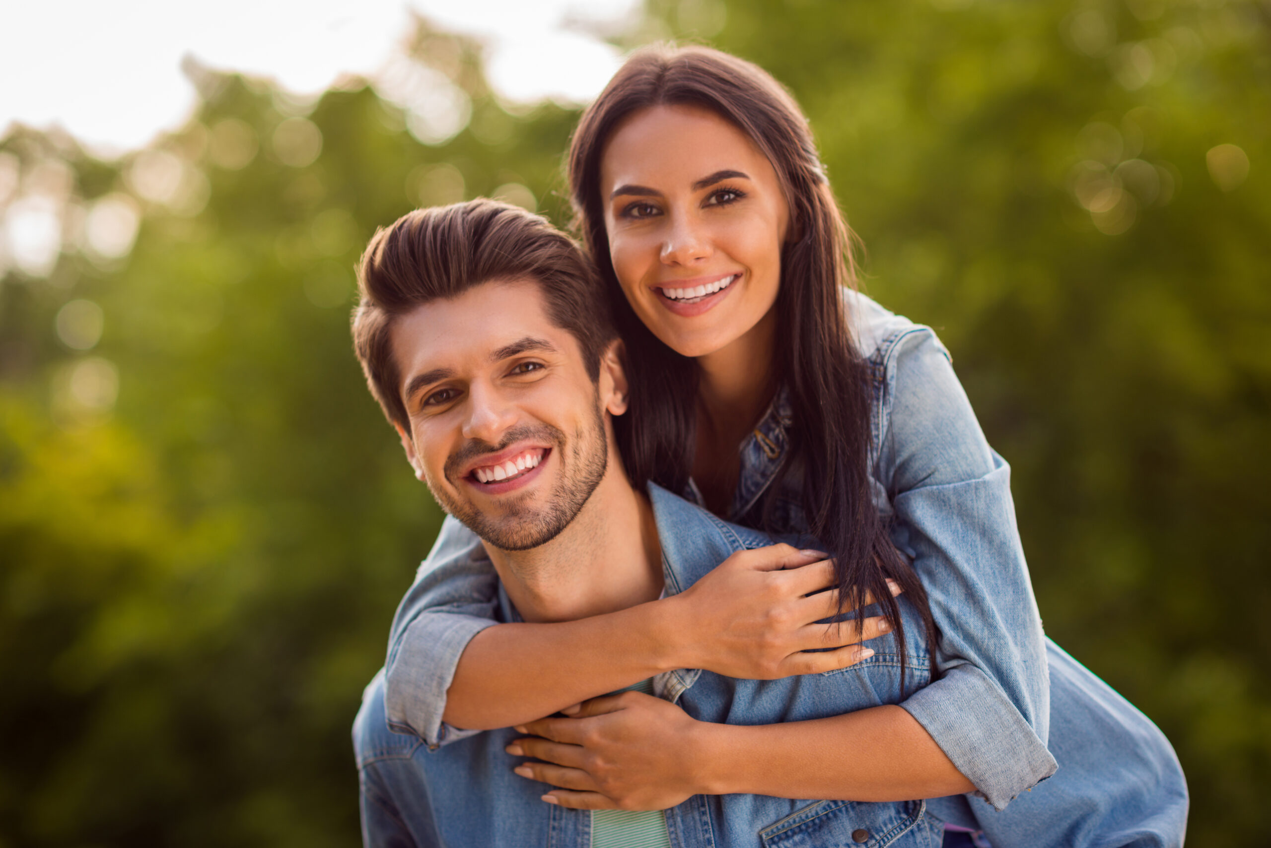 Close up photo of charming couple, piggyback wearing denim jeans outdoors