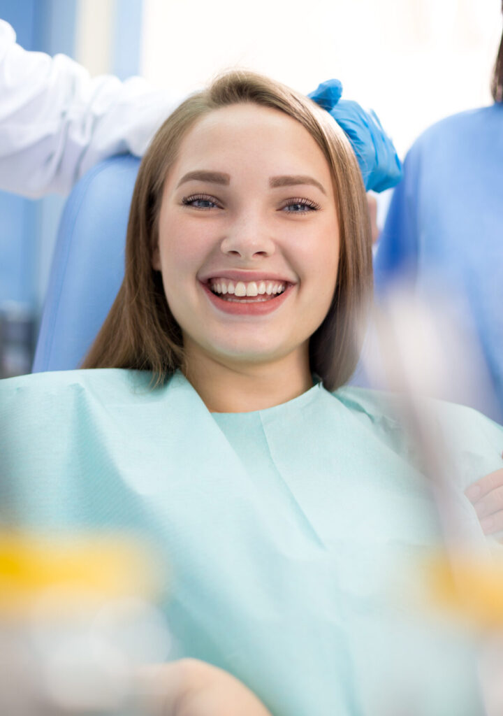 Happy girl in dental chair after treatment when pain stopped in clinic