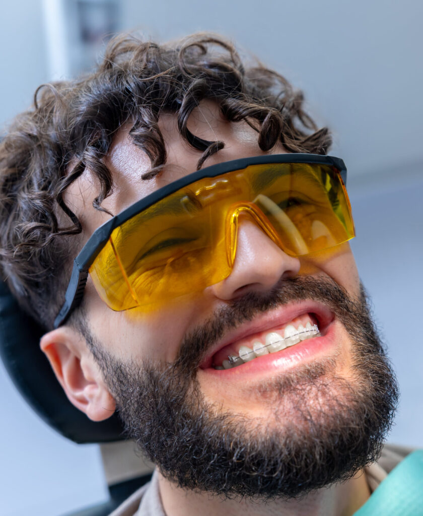 Caucasian man patient during whitening teeth procedures in modern dental clinic
