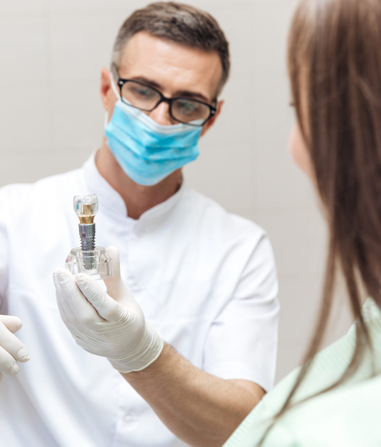 Dentist explaining teeth model to female patient at clinic