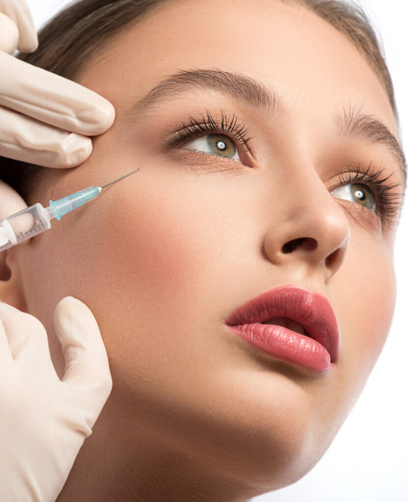 Serine young woman is getting facial botox injection. Beautician hands in gloves holding syringe near her face