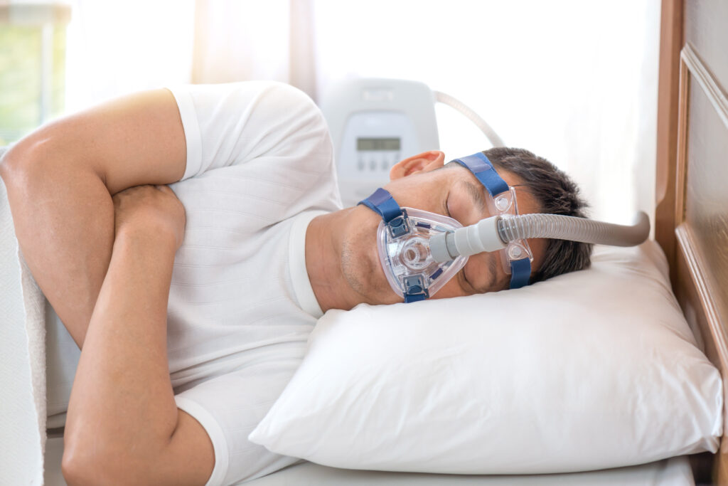 Man sleeping in bed wearing CPAP mask ,sleep apnea therapy Happy and healthy senior man sleeping deeply on his left side without snoring