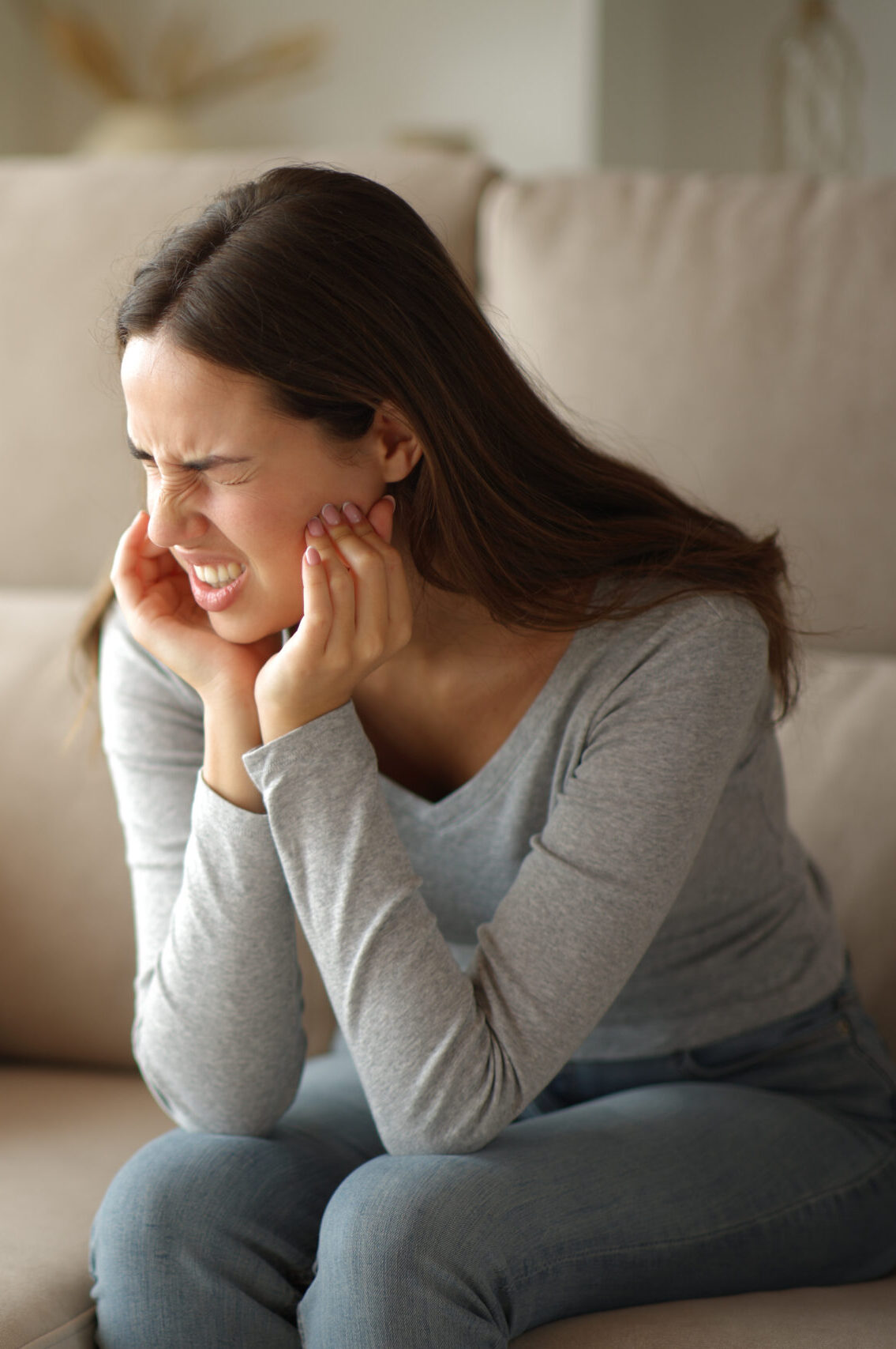Woman suffering tmj syndrome complaining alone sitting on a couch at home