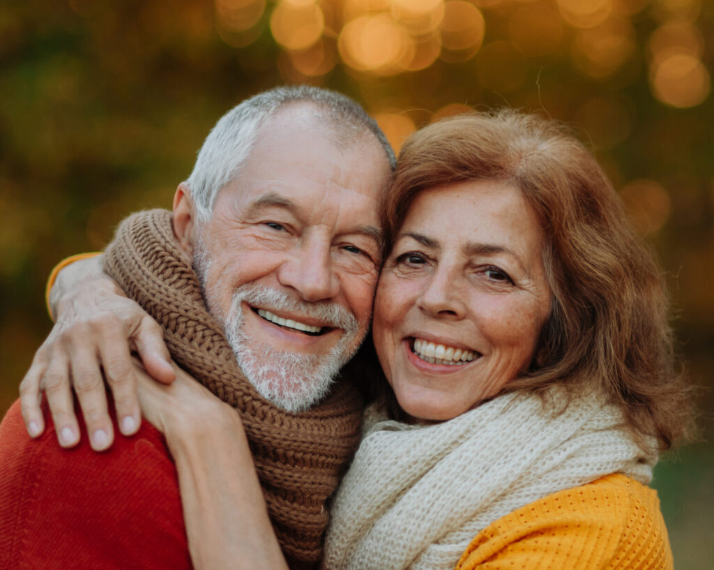 Banner of senior couple in autumn nature, looking at camera, smiling.