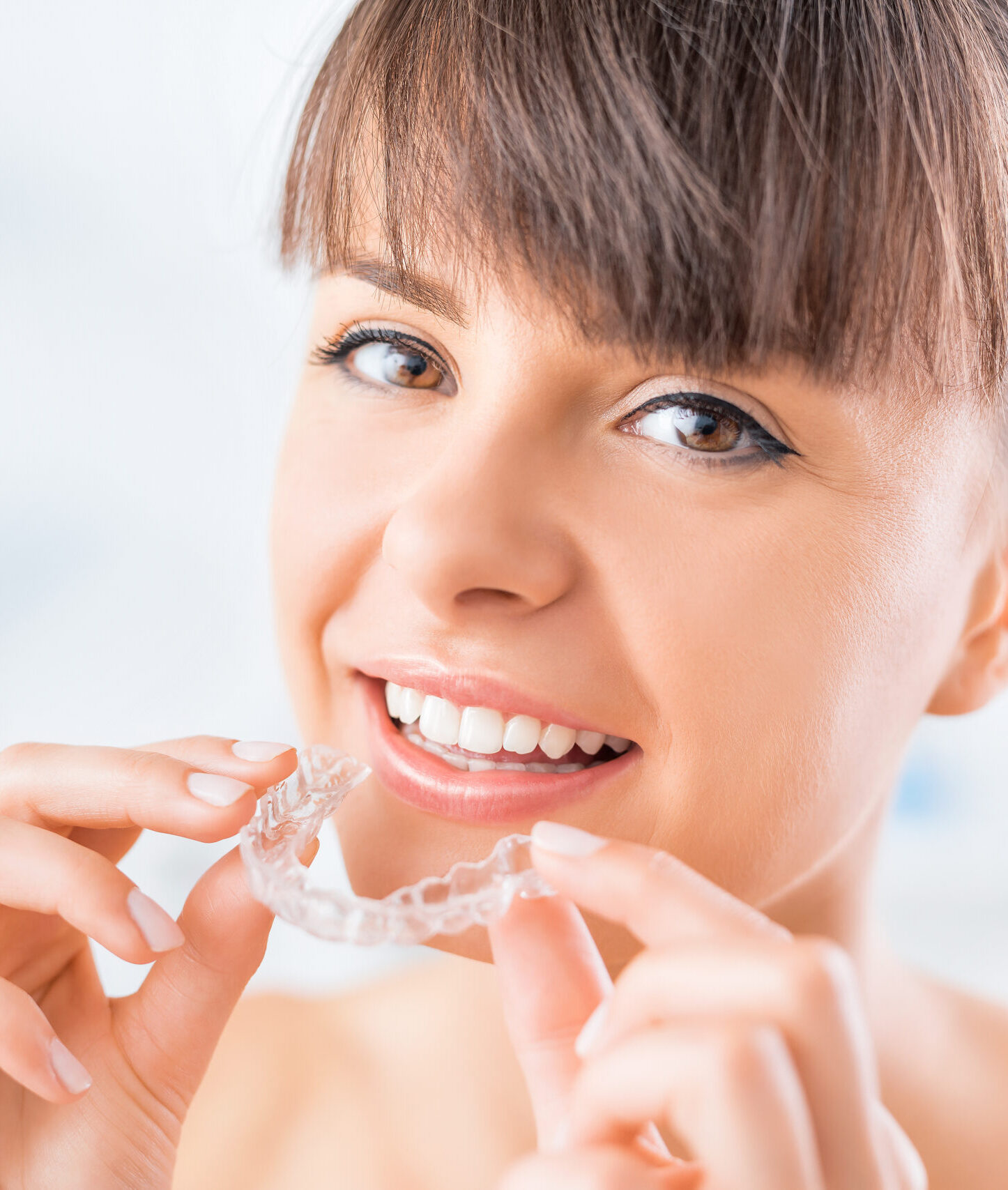 Woman wearing orthodontic silicone trainer. Invisible braces aligner. Mobile orthodontic appliance for dental correction.