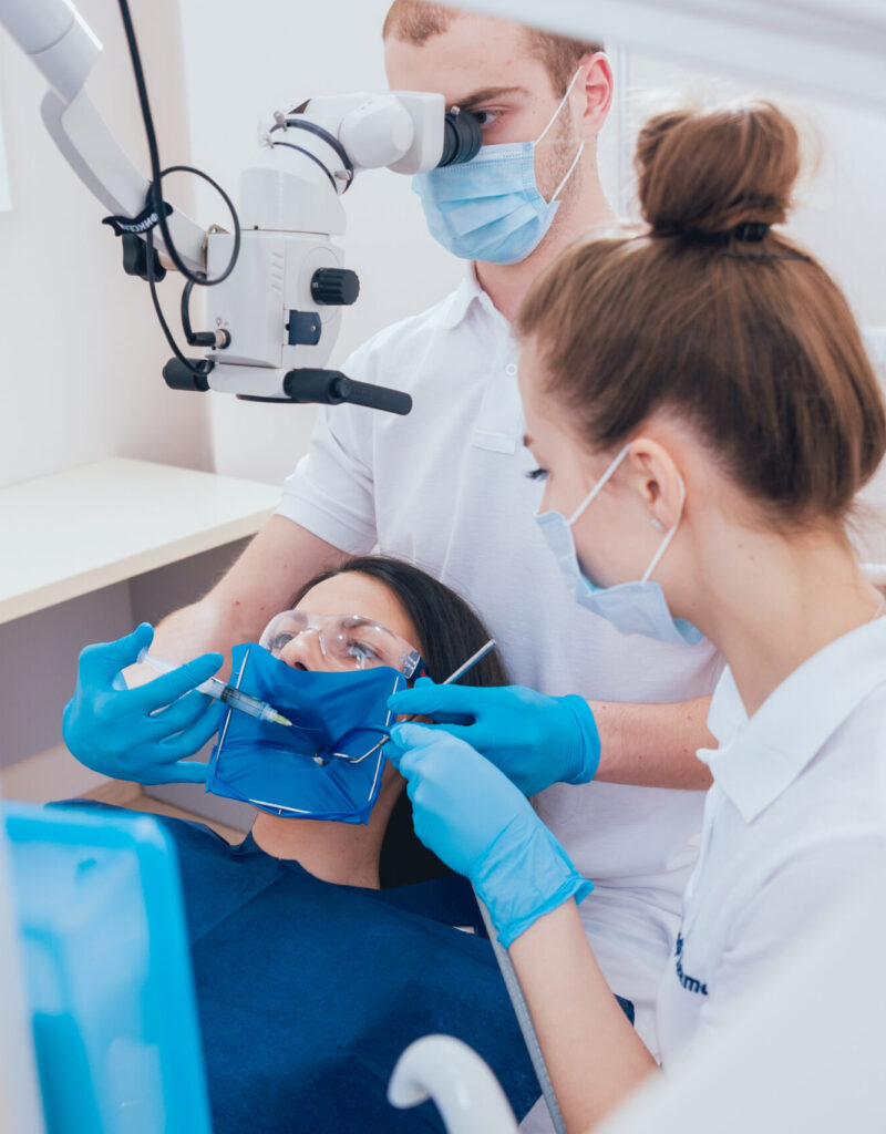 Treatment of root canals under a microscope, work with an assistant. Modern technology