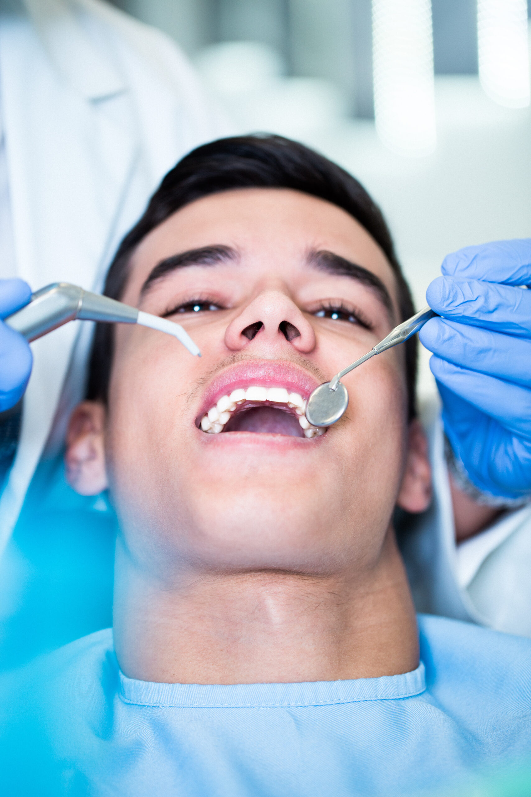 Young attractive man receiving a dental treatment. Close up shot.