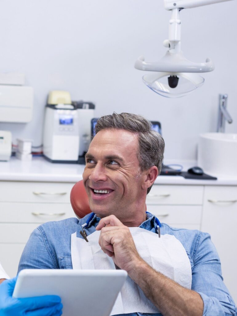 Dentist discussing over digital tablet with male patient