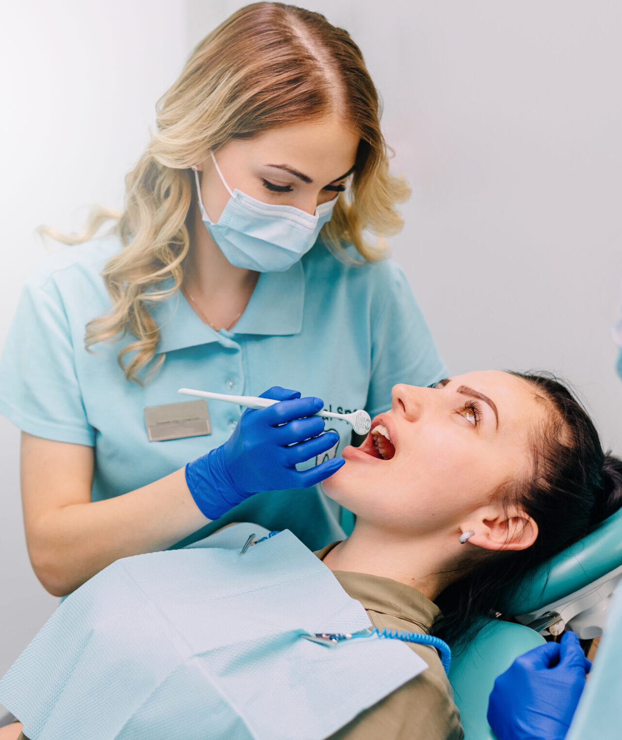 young woman dentist performs examination of patient in clinic
