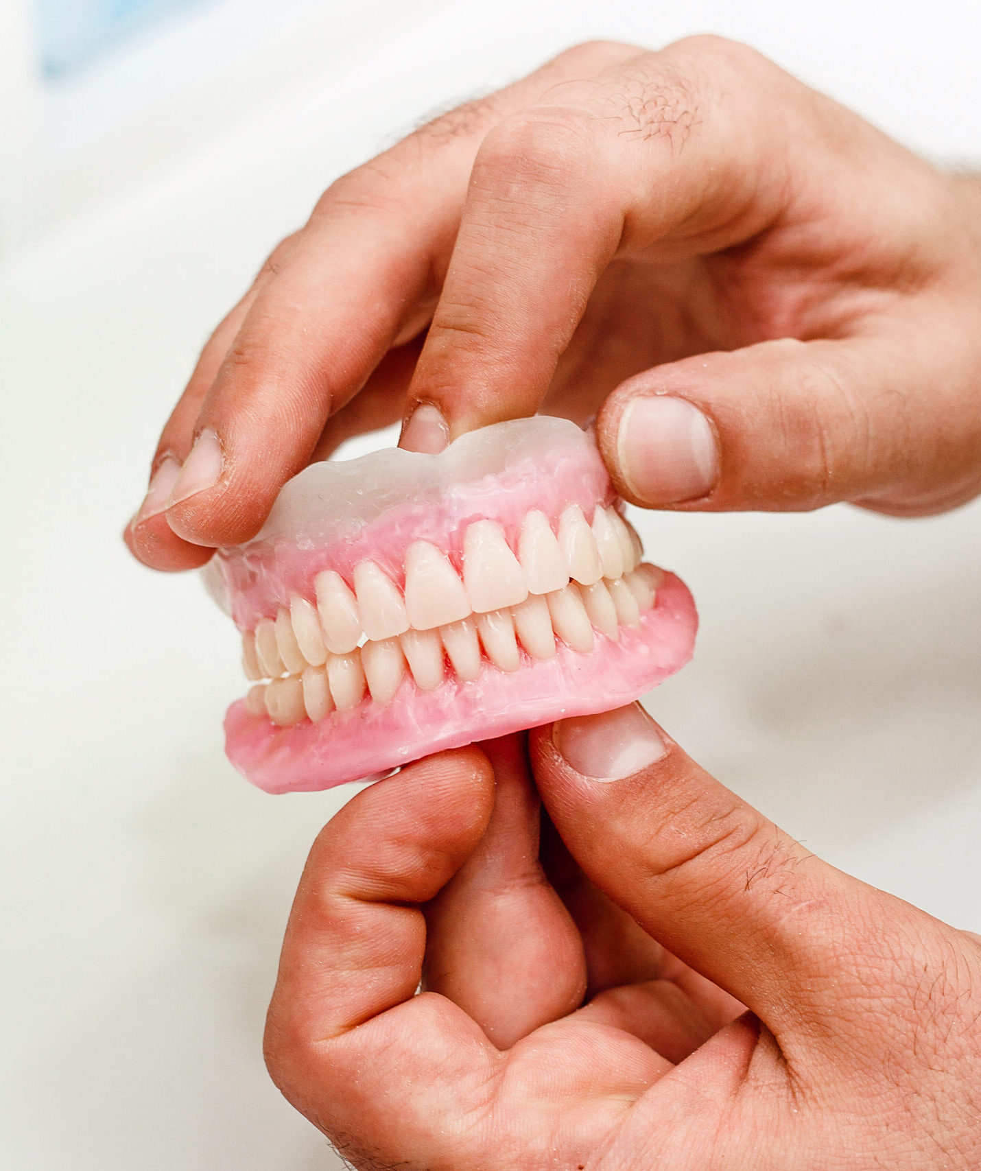 Dental technician holding artificial teeth arrangement of full mouth complete denture