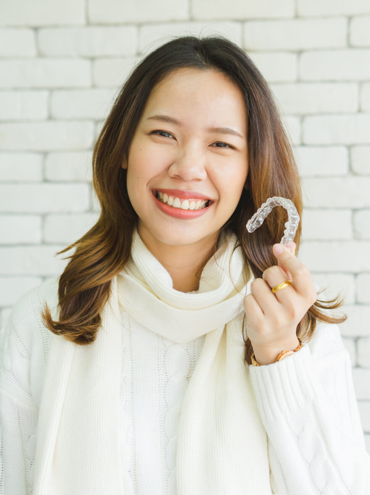 close up young asian woman smiling with hand holding dental aligner retainer (invisible) at dental clinic for beautiful teeth treatment course concept