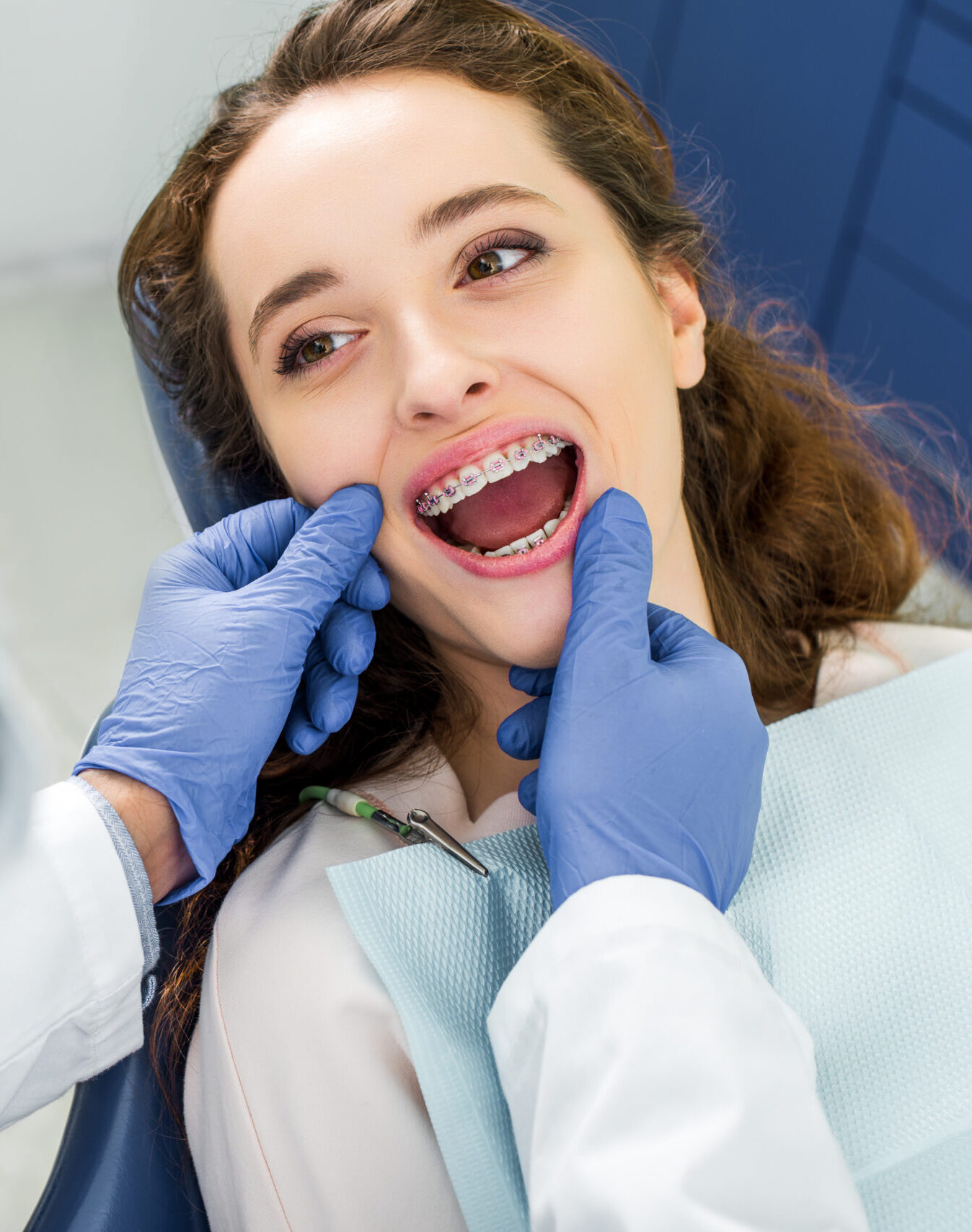 selective focus of woman in braces opening mouth during examination of teeth near dentist