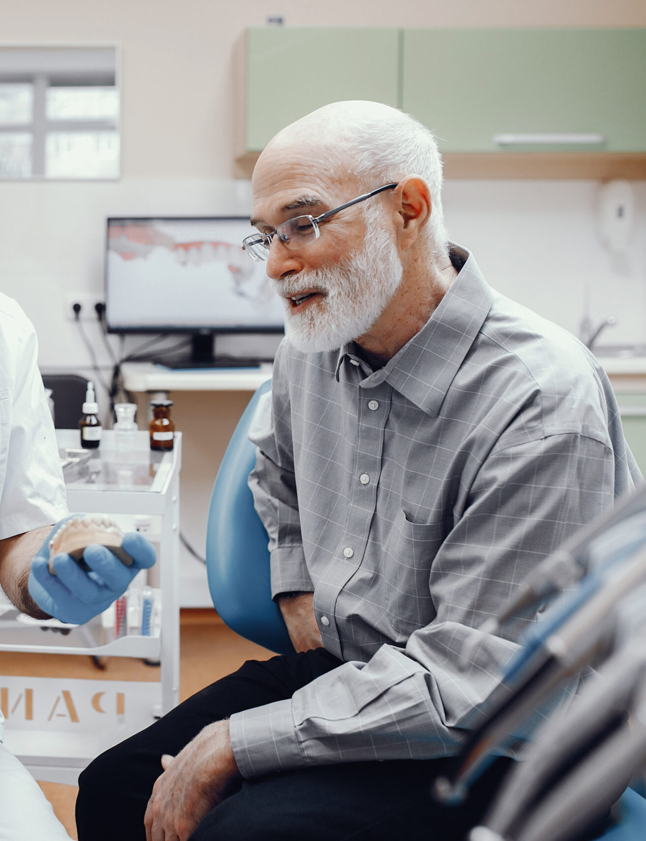 Handsome old man talking to the dendist. Two men in the dentist's office