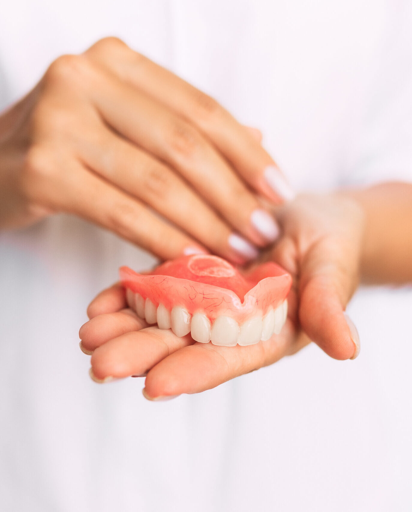 The dentist is holding dentures in his hands. Dental prosthesis in the hands of the doctor close-up. Dentistry conceptual photo. Prosthetic dentistry. False teeth. Removable denture