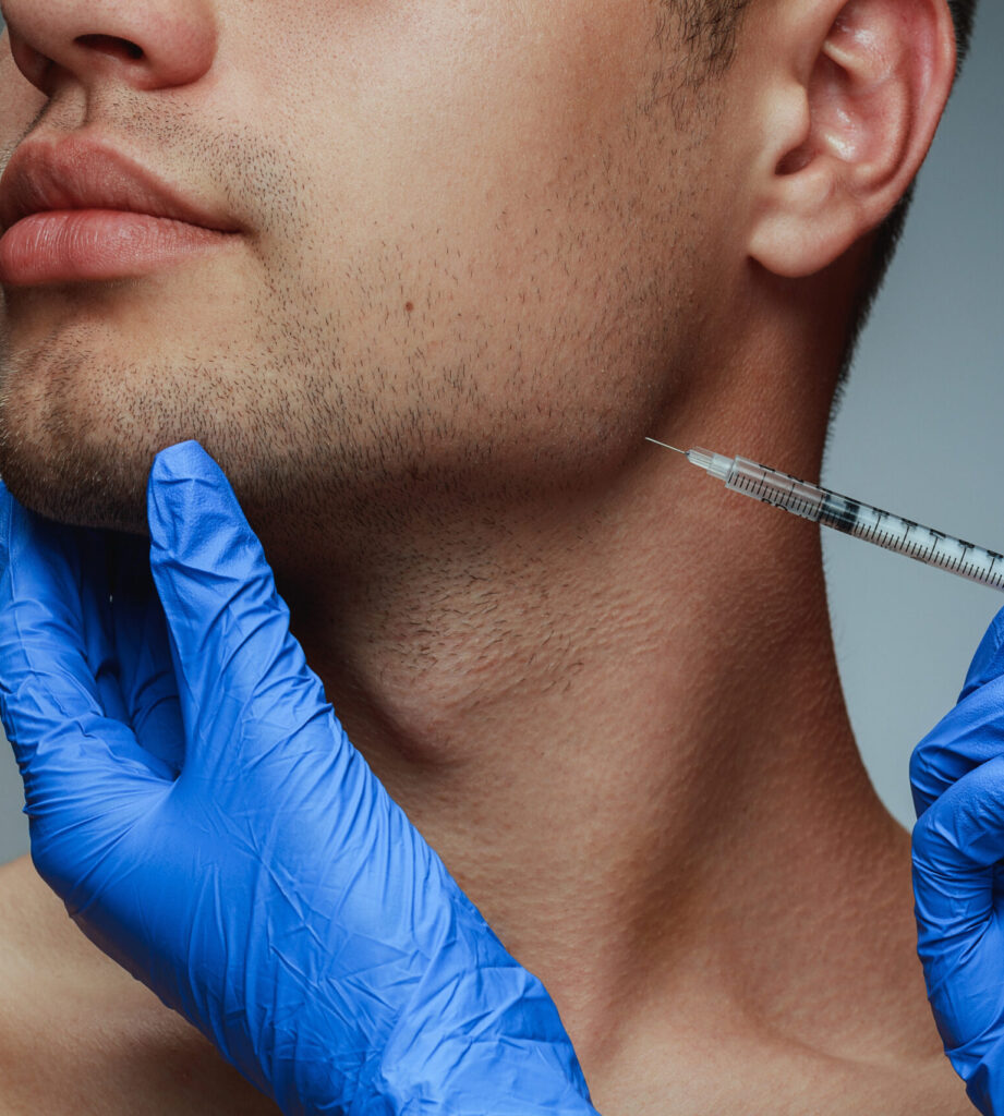 Close-up portrait of young man isolated on grey studio background. Filling botox surgery procedure. Concept of men's health and beauty, cosmetology, self-care, body and skin care. Anti-aging.