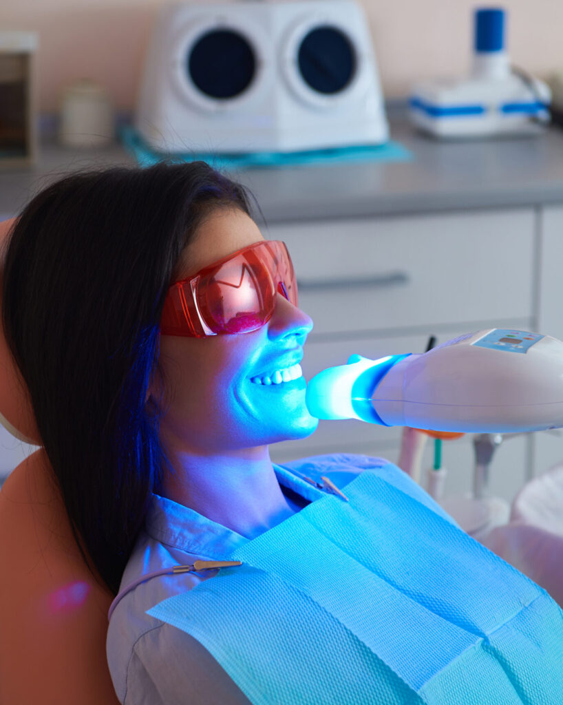 Smiling young woman doing teeth whitening procedure