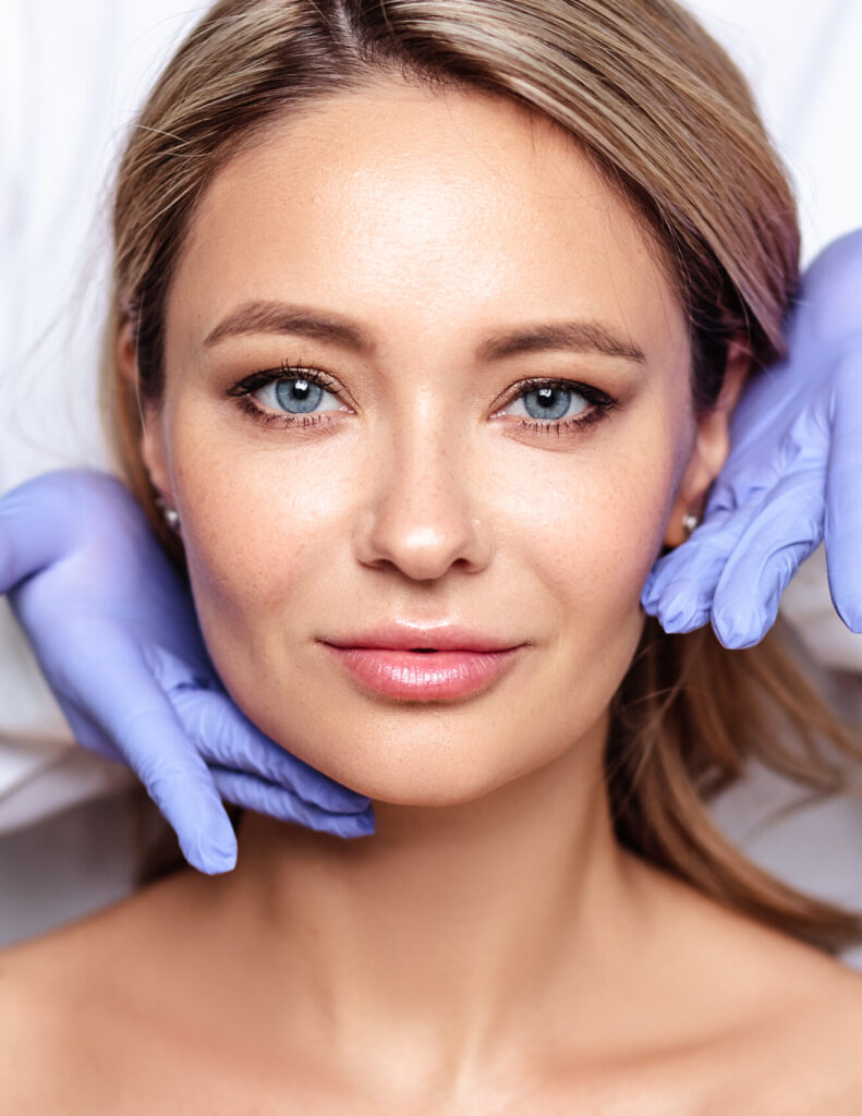 Close up portrait of young blonde woman with cosmetologyst hands