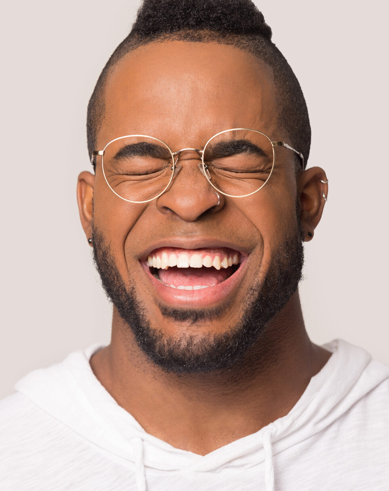 Funny African American man with wide healthy smile laughing at joke close up, happy male in glasses having fun, enjoy laughter, positive emotion, isolated on studio background copy space