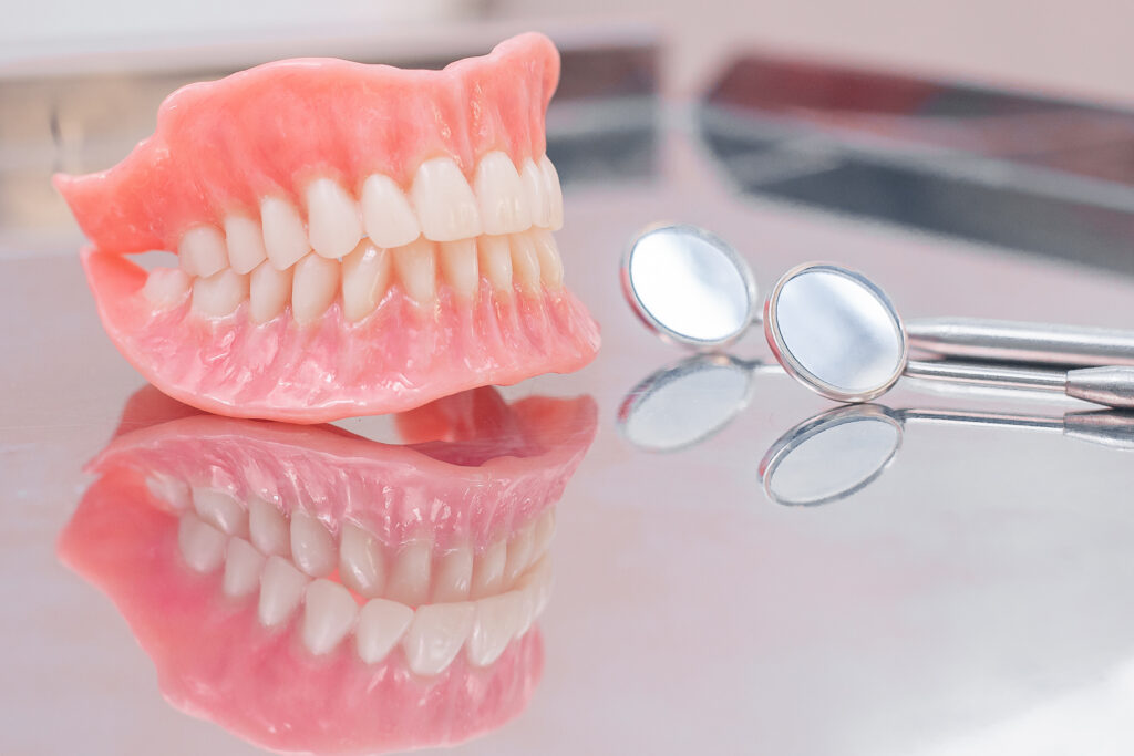 Two dentures. Instruments and dental hygienist checkup concept with teeth model dentures and mouth mirror. Regular dentist checkups