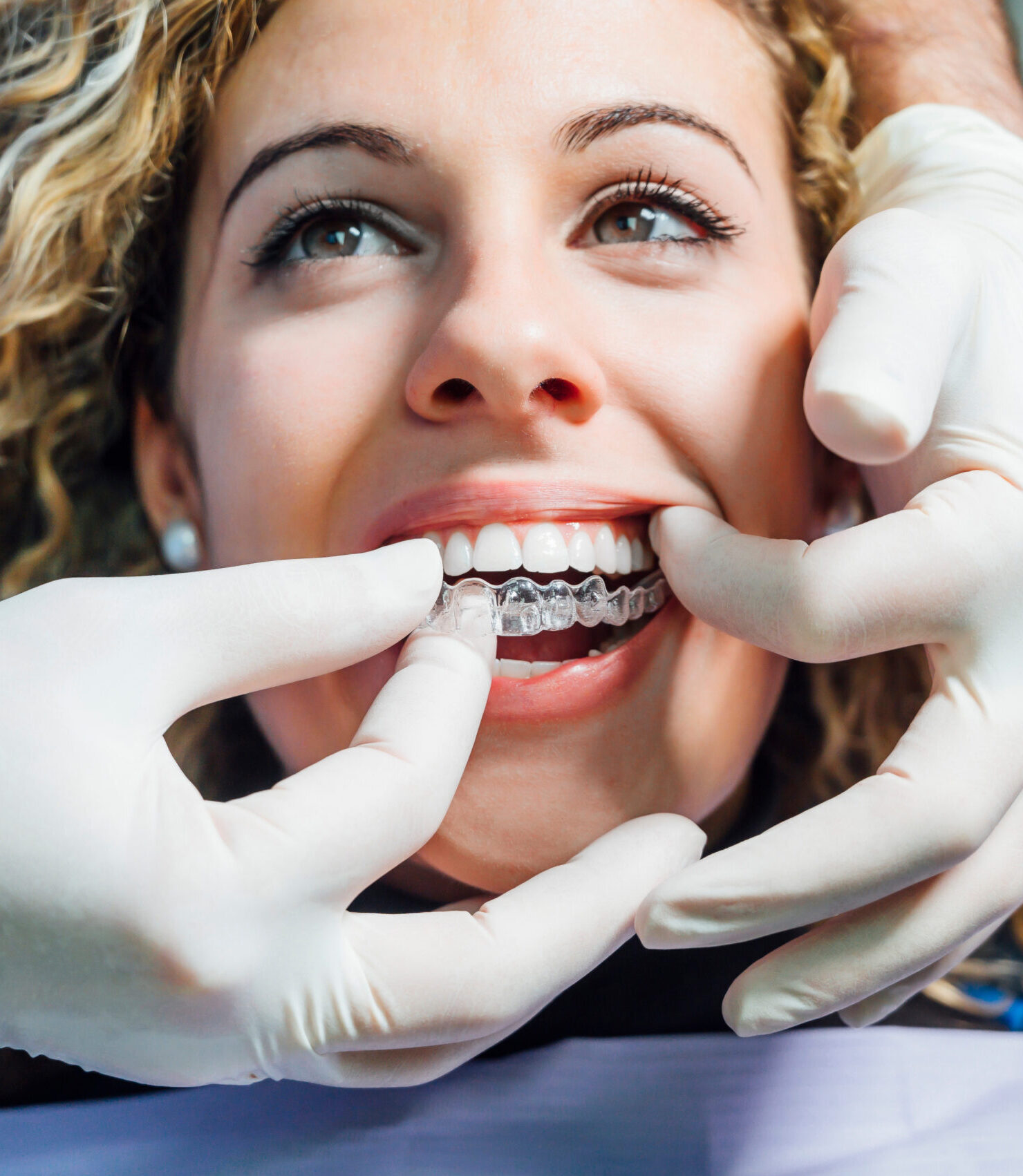 Doctor putting a clear dental aligner to the patient woman