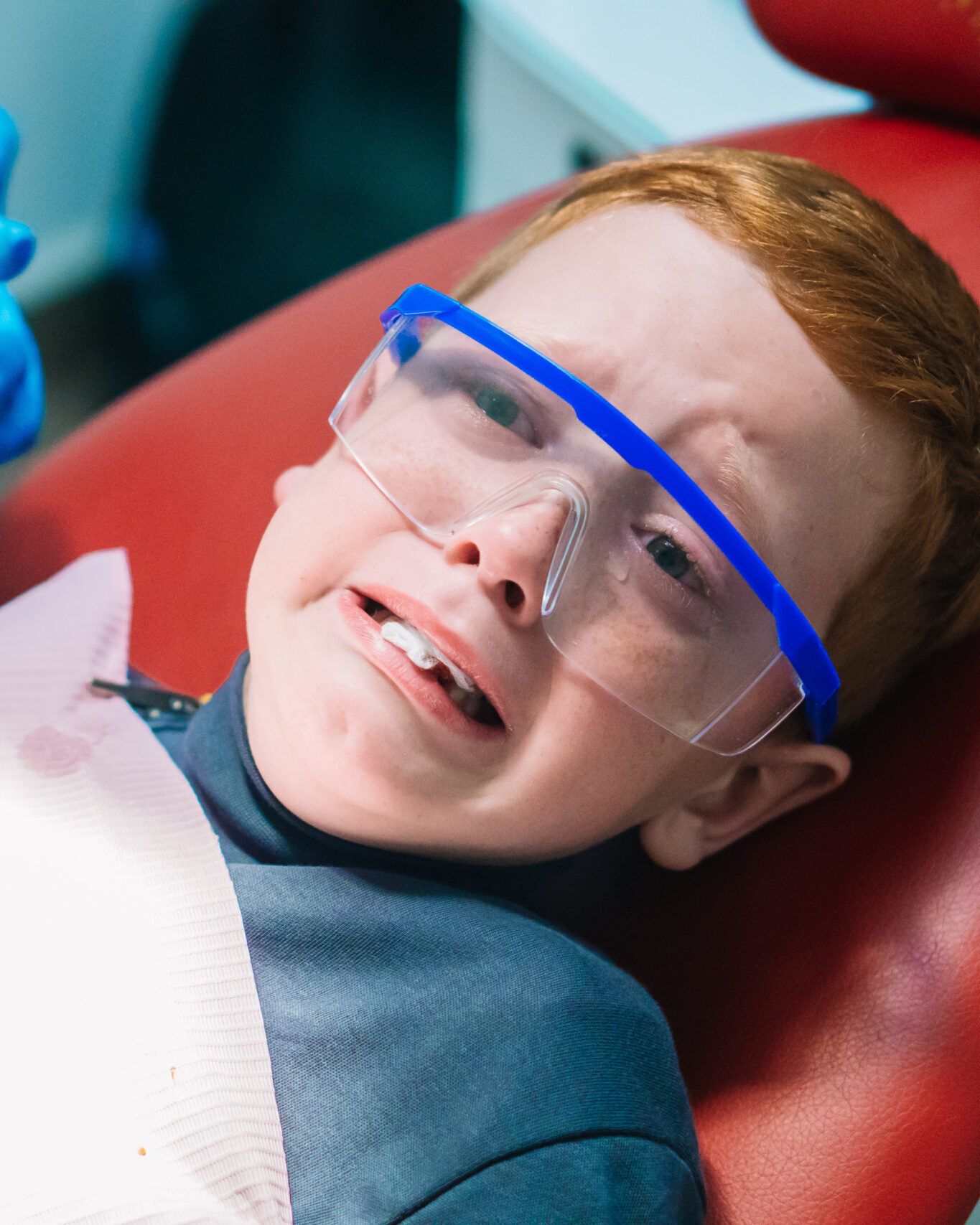 Scared red-haired boy crying at reception at dentist in dental chair. Pediatric dentistry