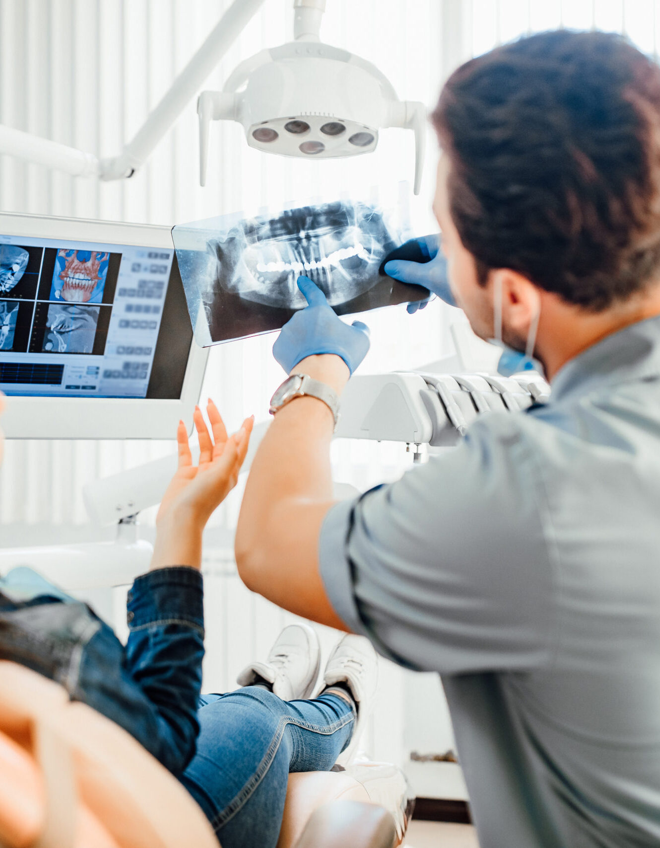 Medicine, dentistry and healthcare concept, male dentist showing teeth x-ray to female patient at dental clinic office.