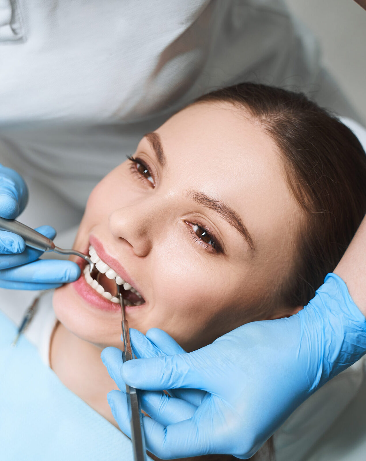 Young female is lying in dental chair during procedures for healing her teeth with equipment