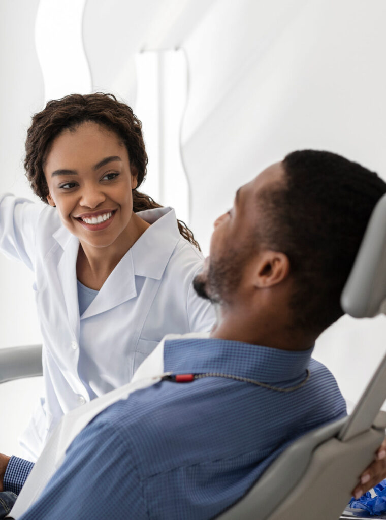 Beautiful black woman dentist greeting male patient on her workplace, copy space