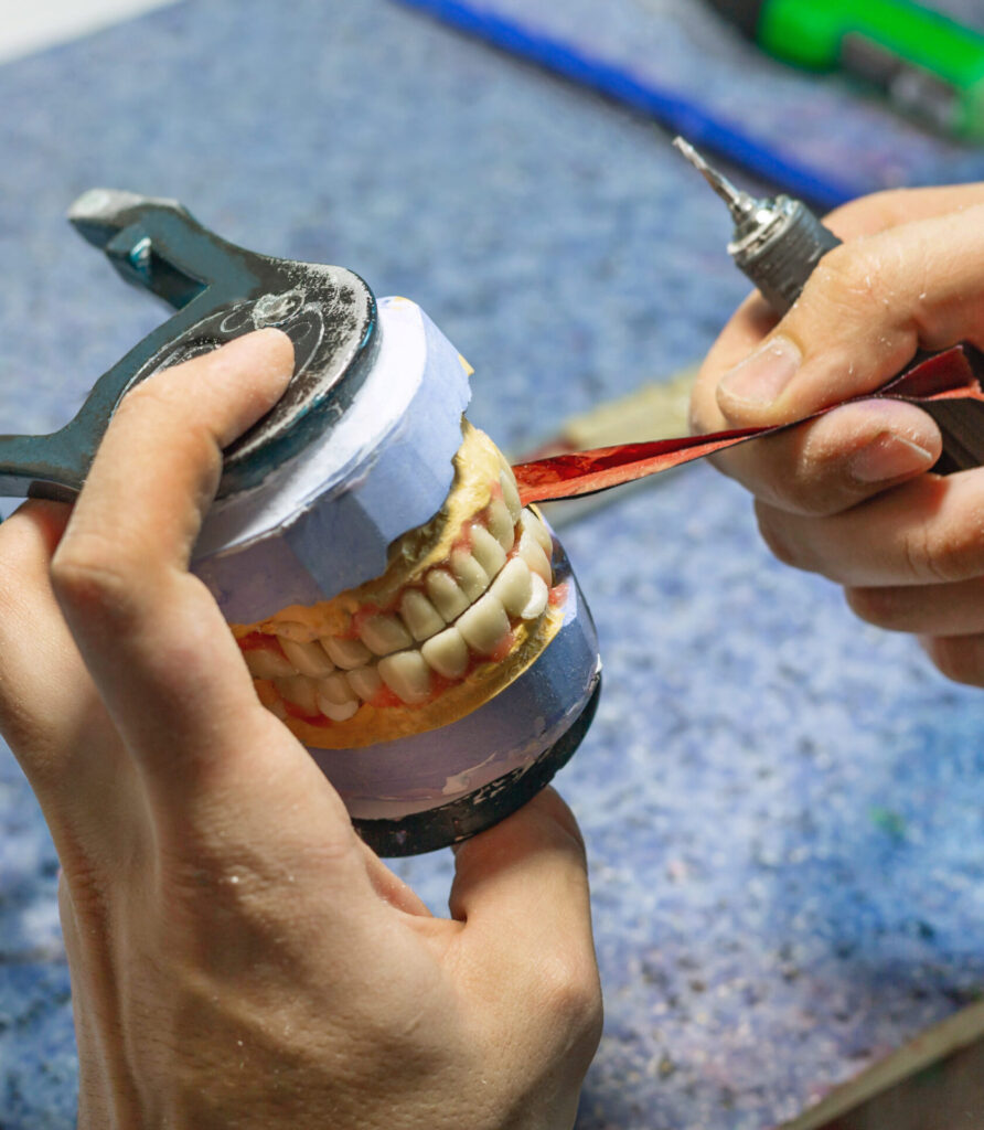 Workplace of a dental technician. Checking the occlusion of the jaw prosthesis using a special tape. Close up, selective focus