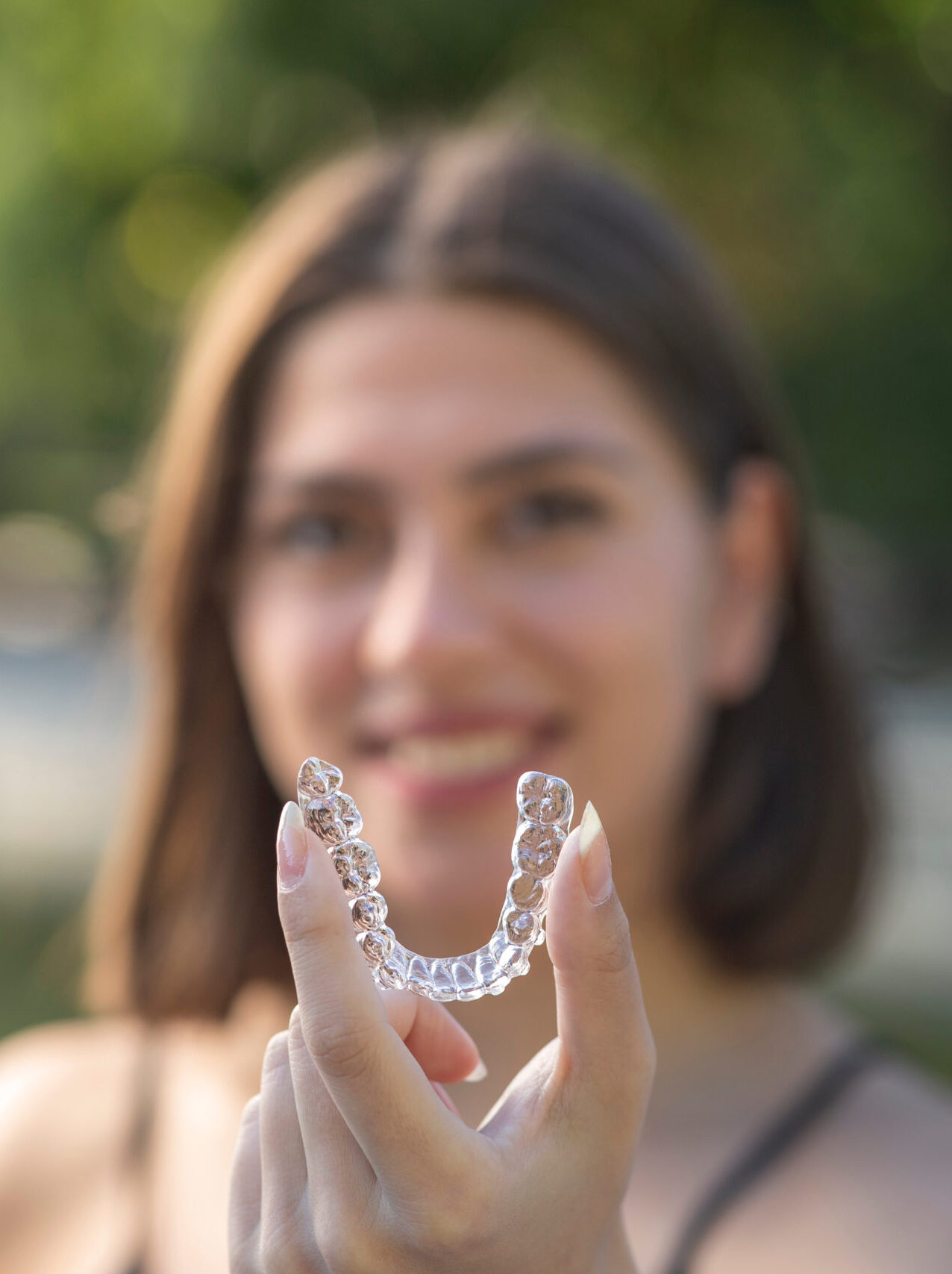 Beautiful smiling Turkish woman is holding an invisalign bracer