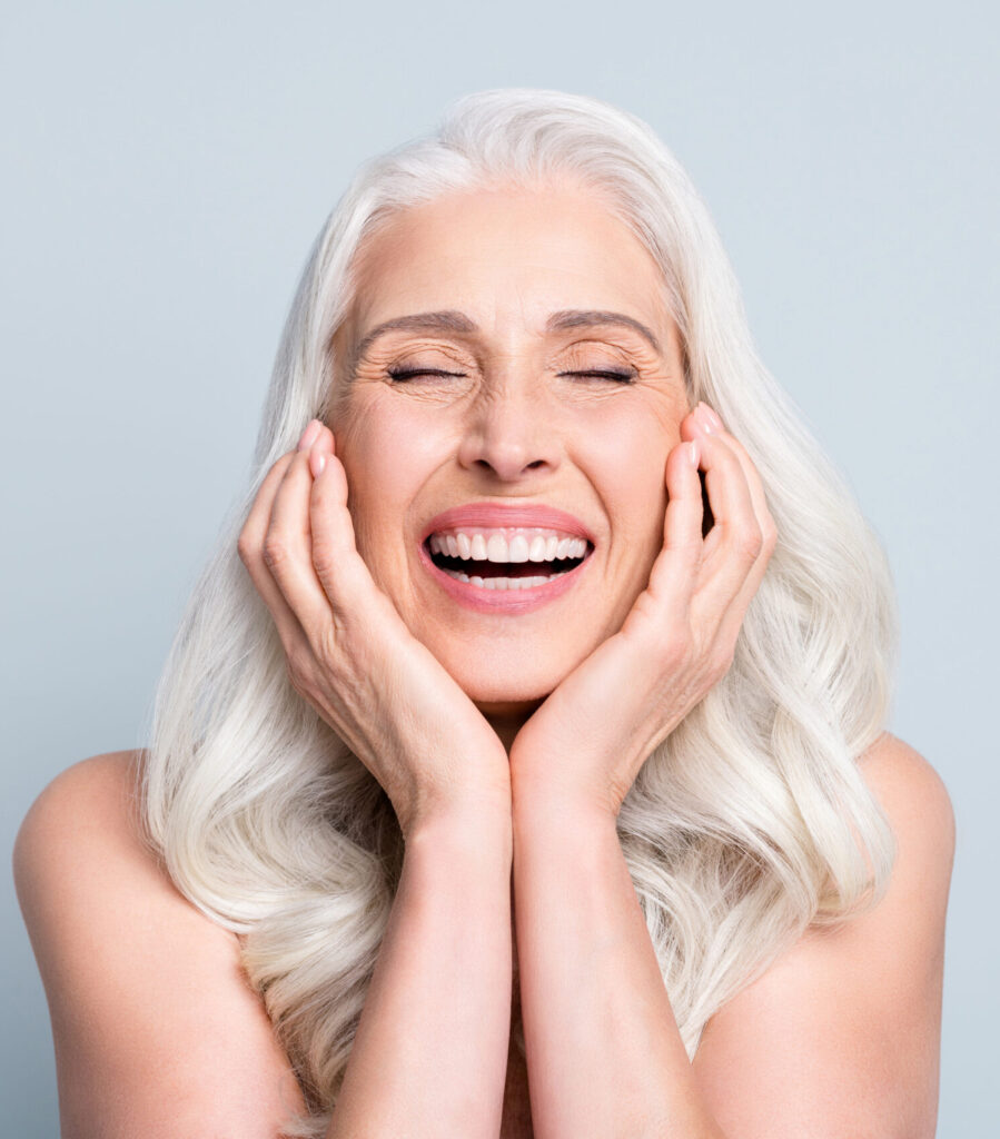 Close-up portrait of her she nice attractive excited cheerful grey-haired elderly lady touching cheeks laughing isolated gray pastel color background.