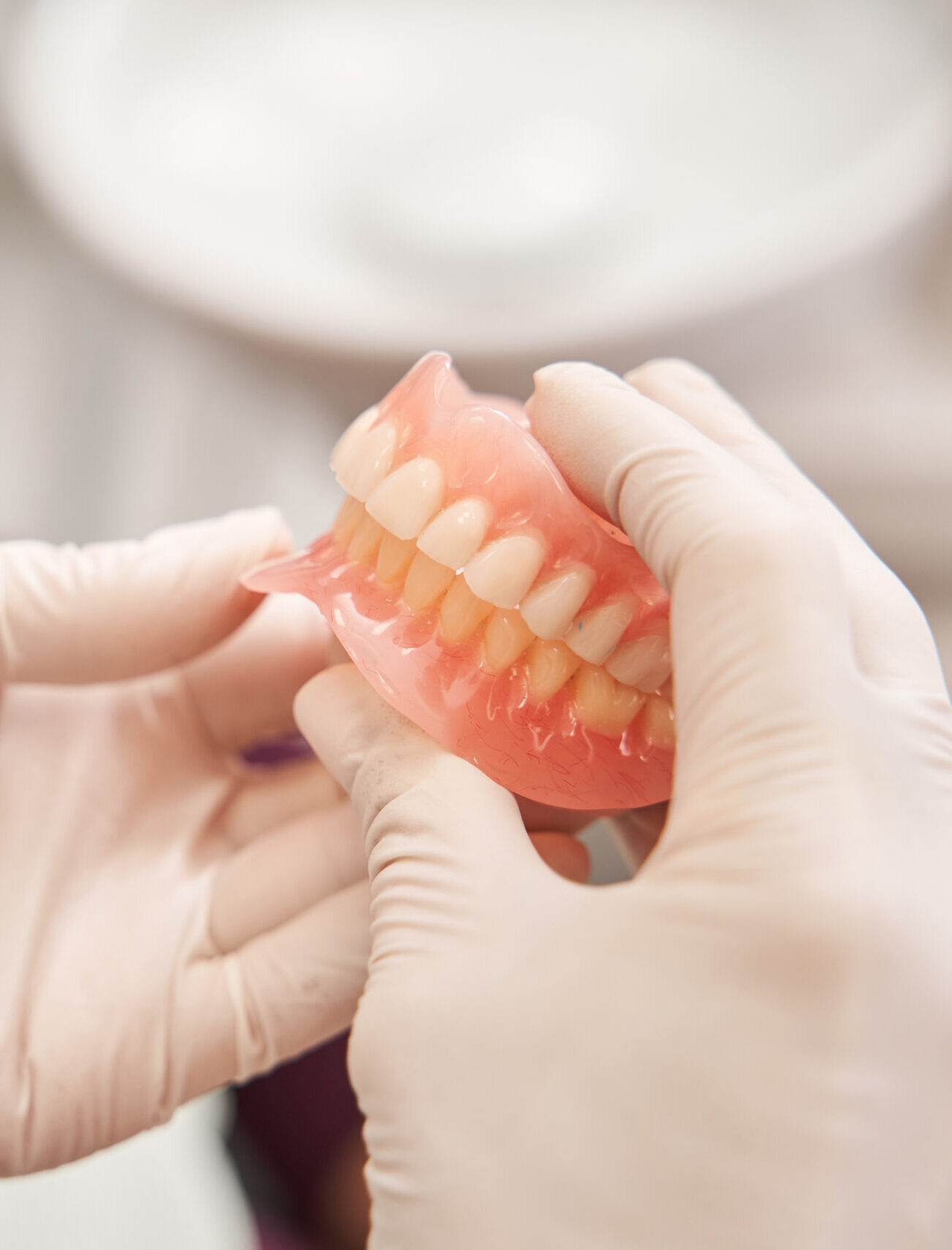 Cropped view of the dentist holding dentures in her hands. Dental prosthesis in the hands of the doctor close-up. Front view of complete denture. Dentistry conceptual photo. Prosthetic dentistry. False teeth