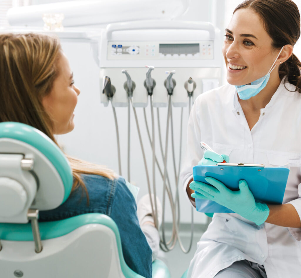 European mid dentist woman smiling while working with patient in dental clinic