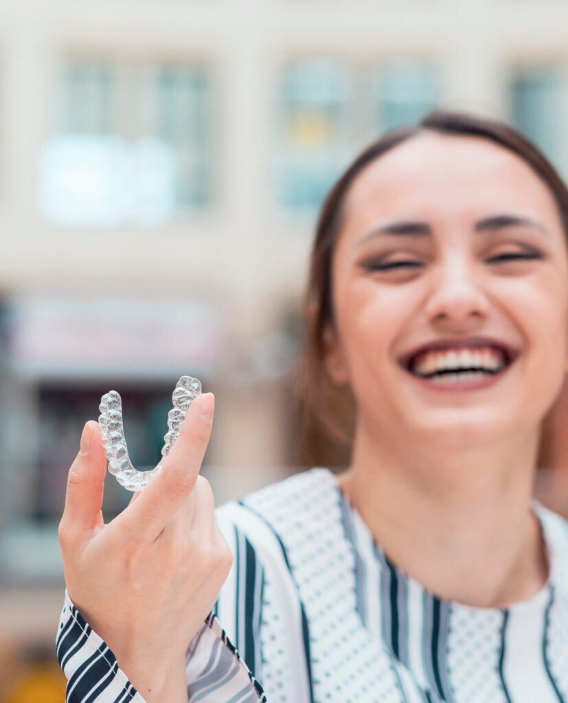 Beautiful smiling Turkish woman is holding an invisaligner