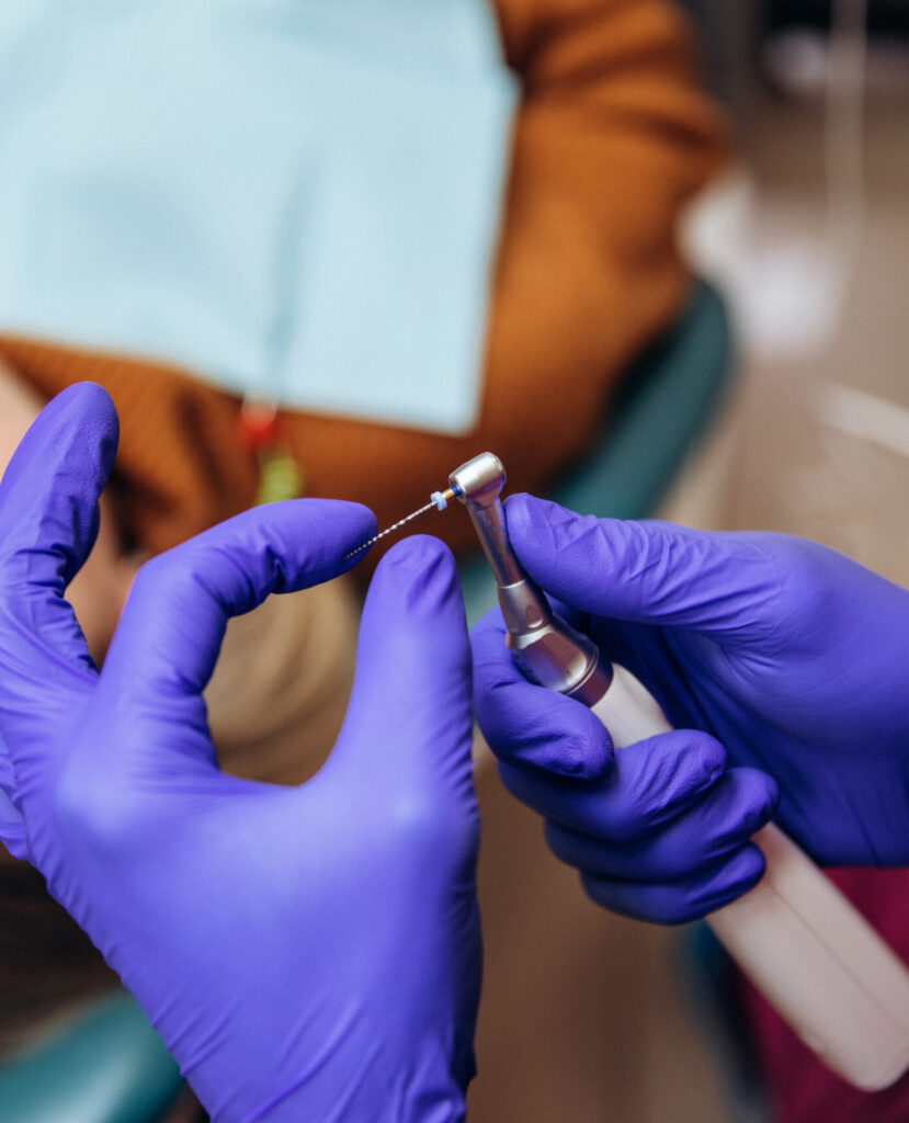 Closeup picture of dental instruments: drill and needle for root canal treatment and pulpitis in hand at the dentist