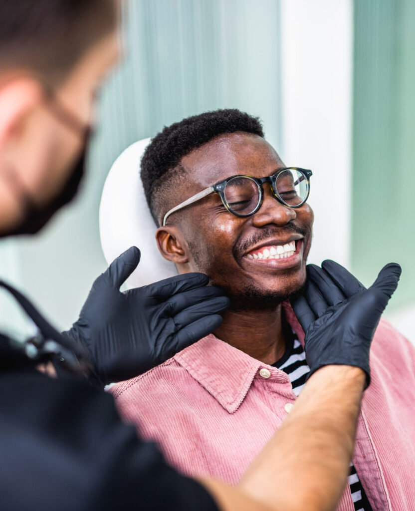 African American young man having a visit at the dentist's. He is sitting on chair at dentist office in dental clinic.