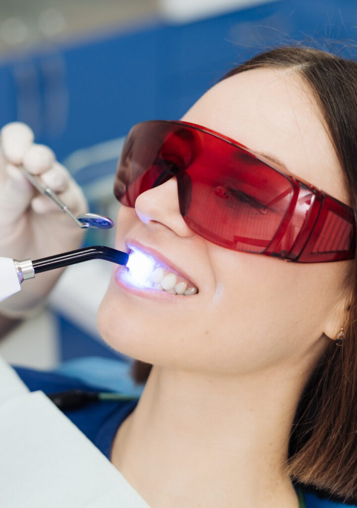 Close-up portrait of a female patient visiting dentist for teeth whitening in clinic