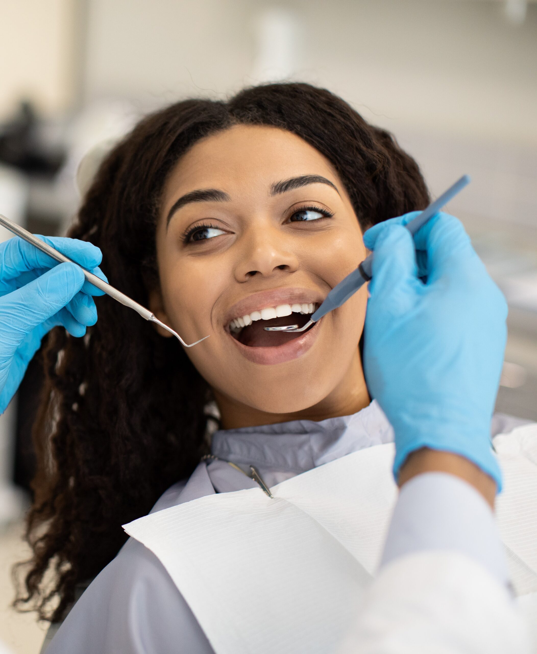 Young African American Woman Having Check Up With Dentist In Modern Clinic, Black Lady Sitting In Chair With Opened Mouth And Looking At Doctor With Dental Tools In Hands, Closeup, Selective Focus