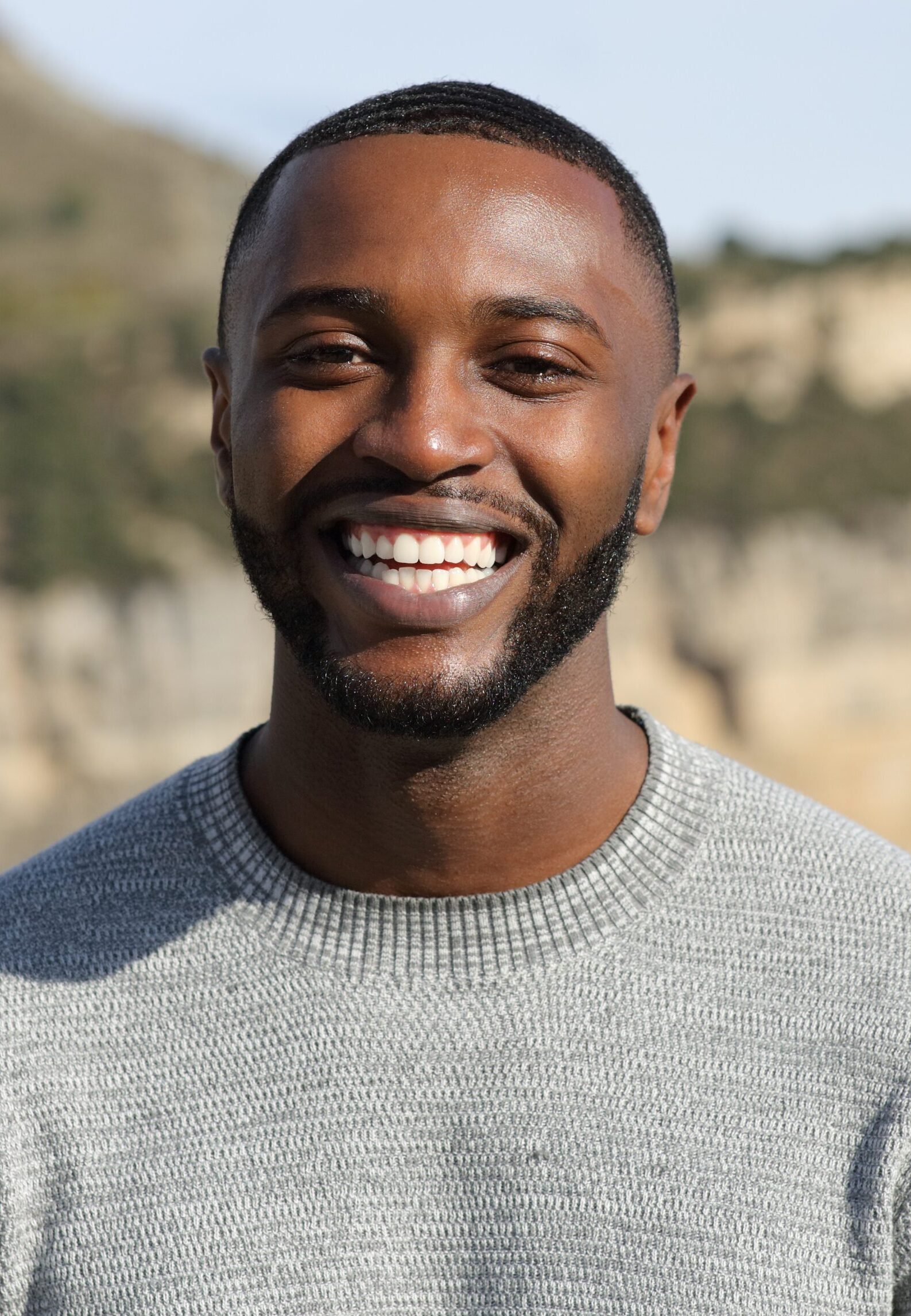 Happy man with black skin smiling at camera in the mountain