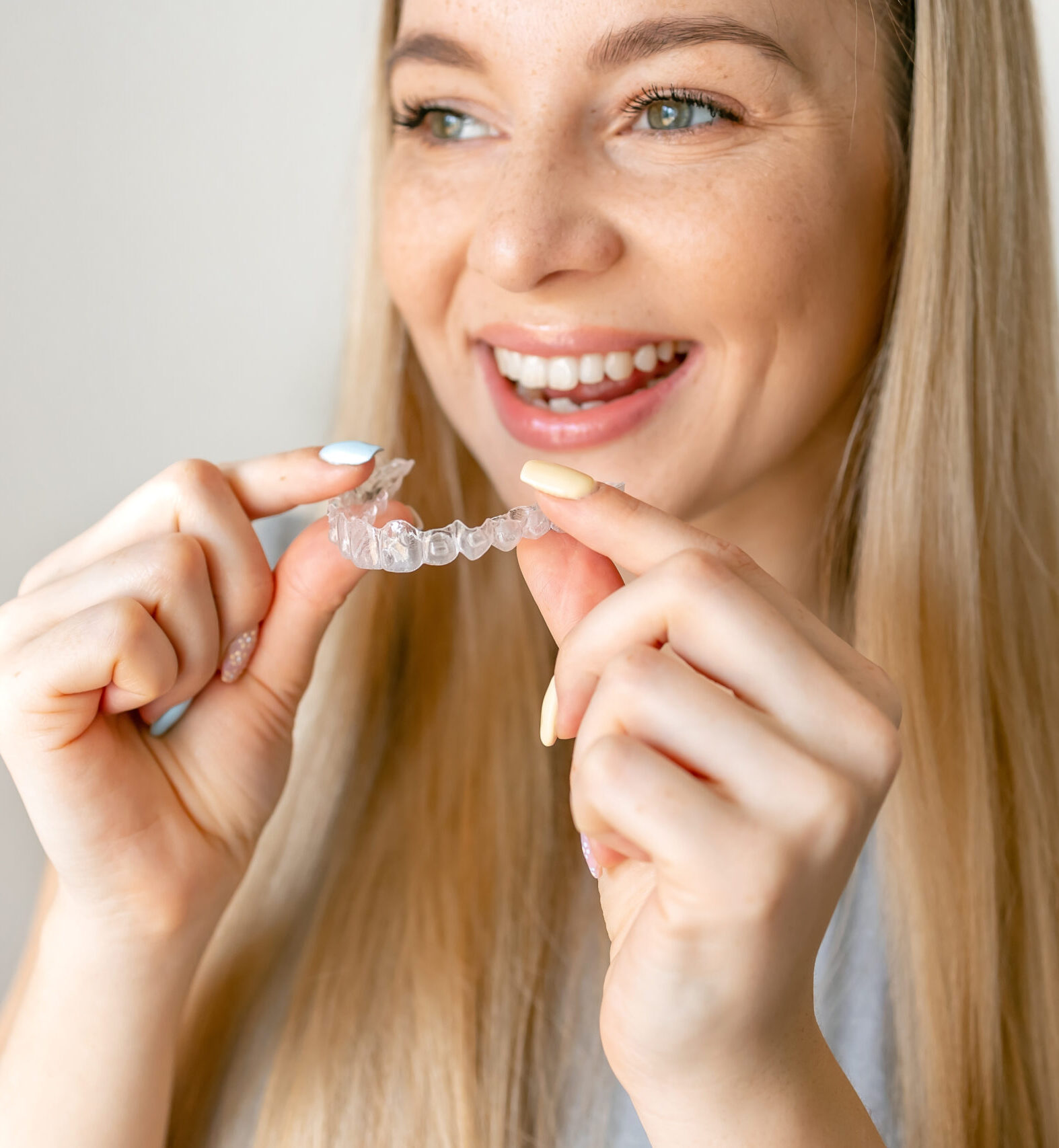 Dental care. Smiling woman with healthy teeth using removable clear braces aligner, orthodontic silicone trainer.