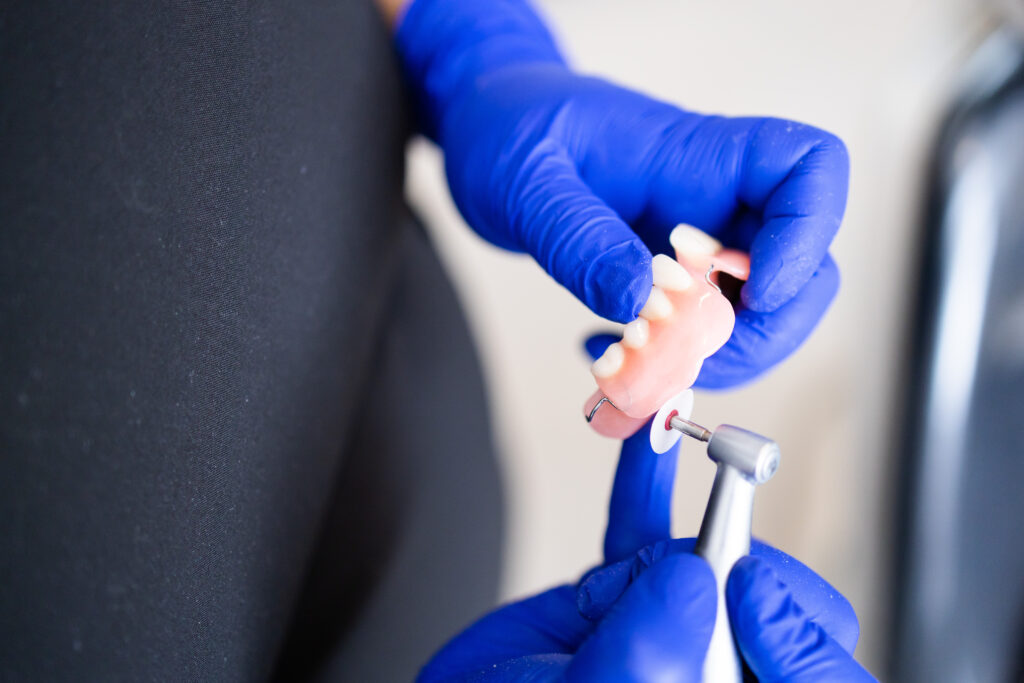 Unrecognizable Dentist's hands finishing a polishing dental prosthesis. Composite restorations. Dental tooth plate. Copy space. Horizontal