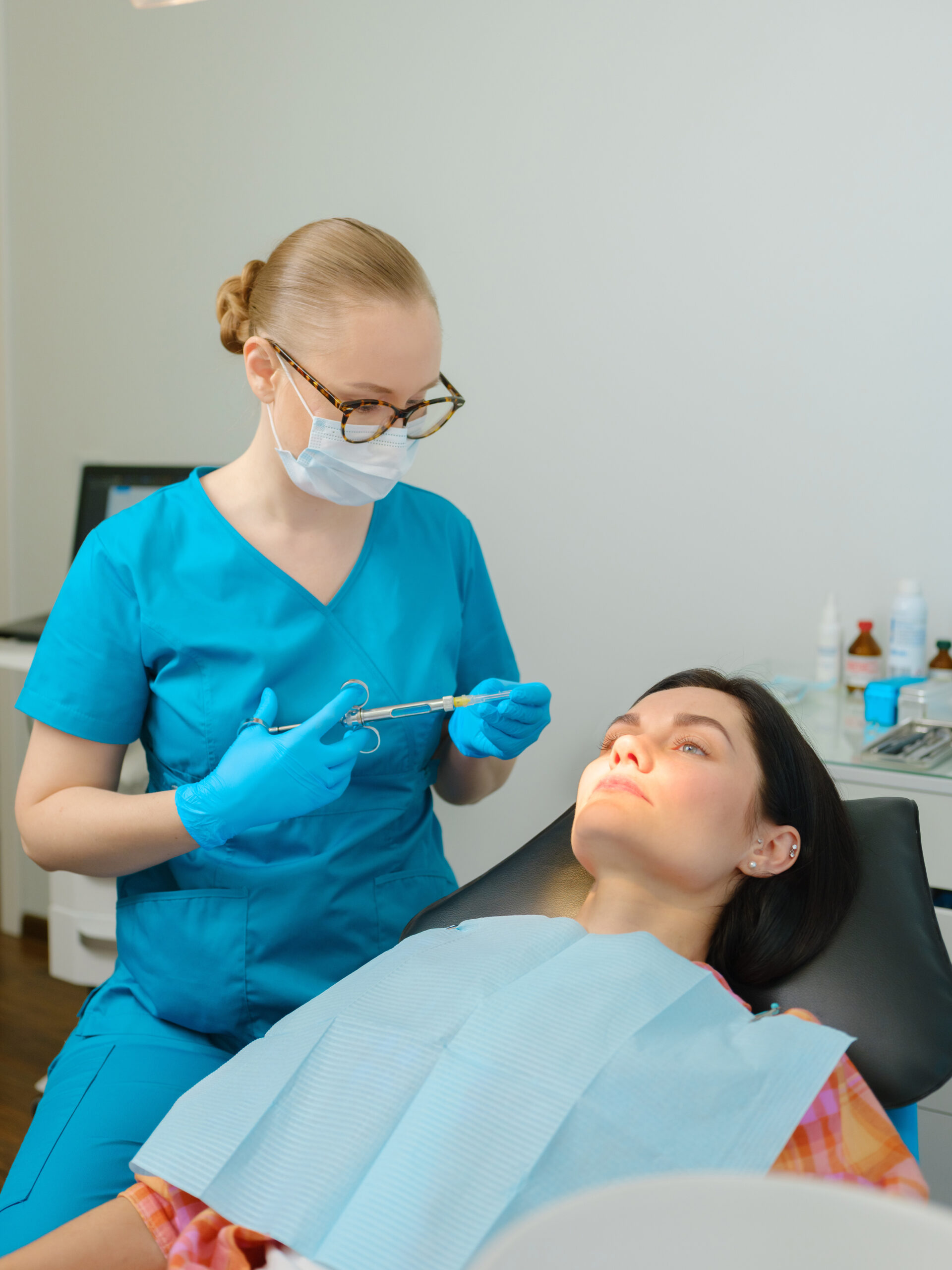Female dentist with cartridge syringe getting ready to use anesthesia before teeth treatment