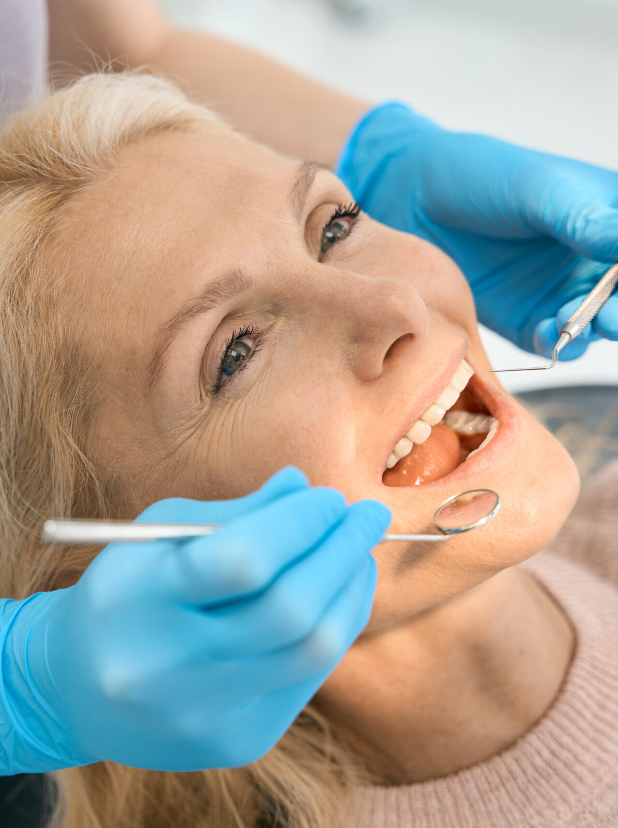 Female patient visiting dantist for examining mouth with the mirror