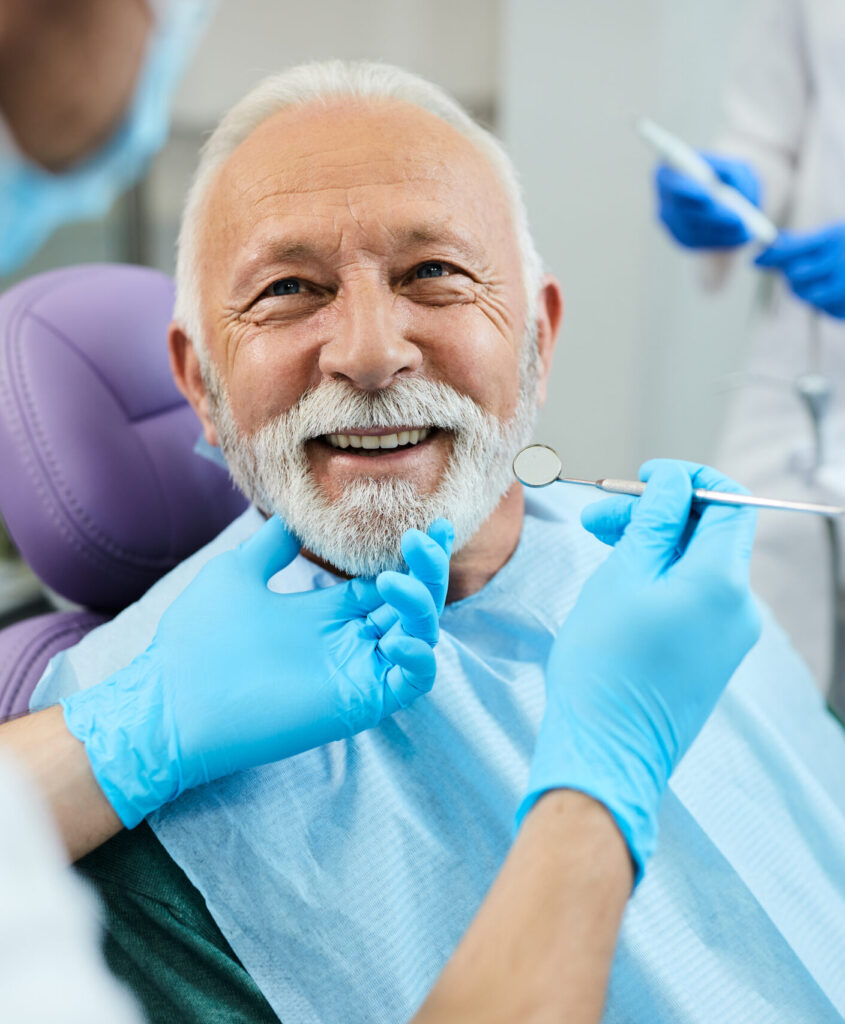 Happy senior man having dental treatment at dentist's office.