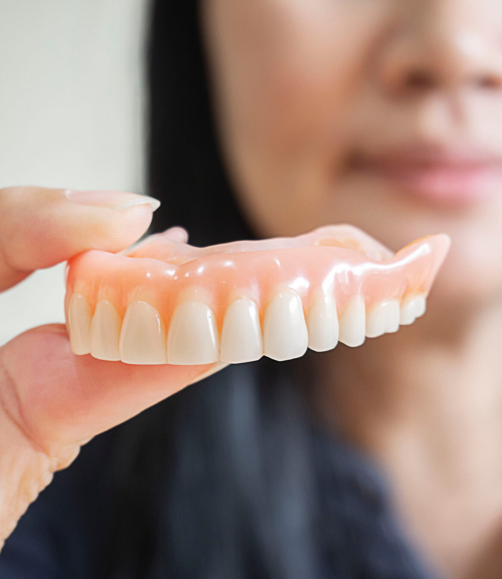 Happy asian woman be smile and holding dentures in hand. Dentures for prosthetic devices constructed to replace missing teeth and helping to chew food.