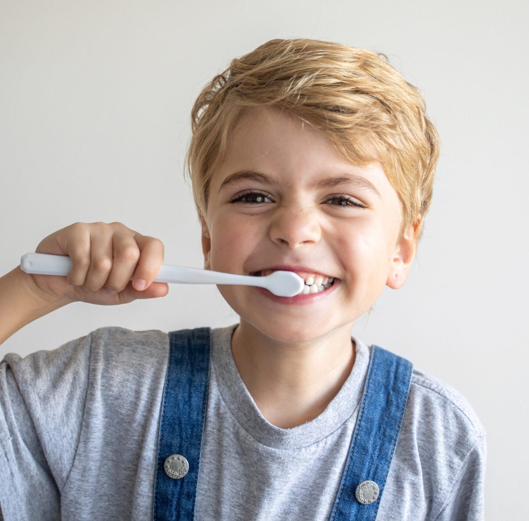 Cute child brush teeth toothbrush, smiling over white background. Studio shot. Dental hygiene, morning routine, lifestyle, tooth care, children health.