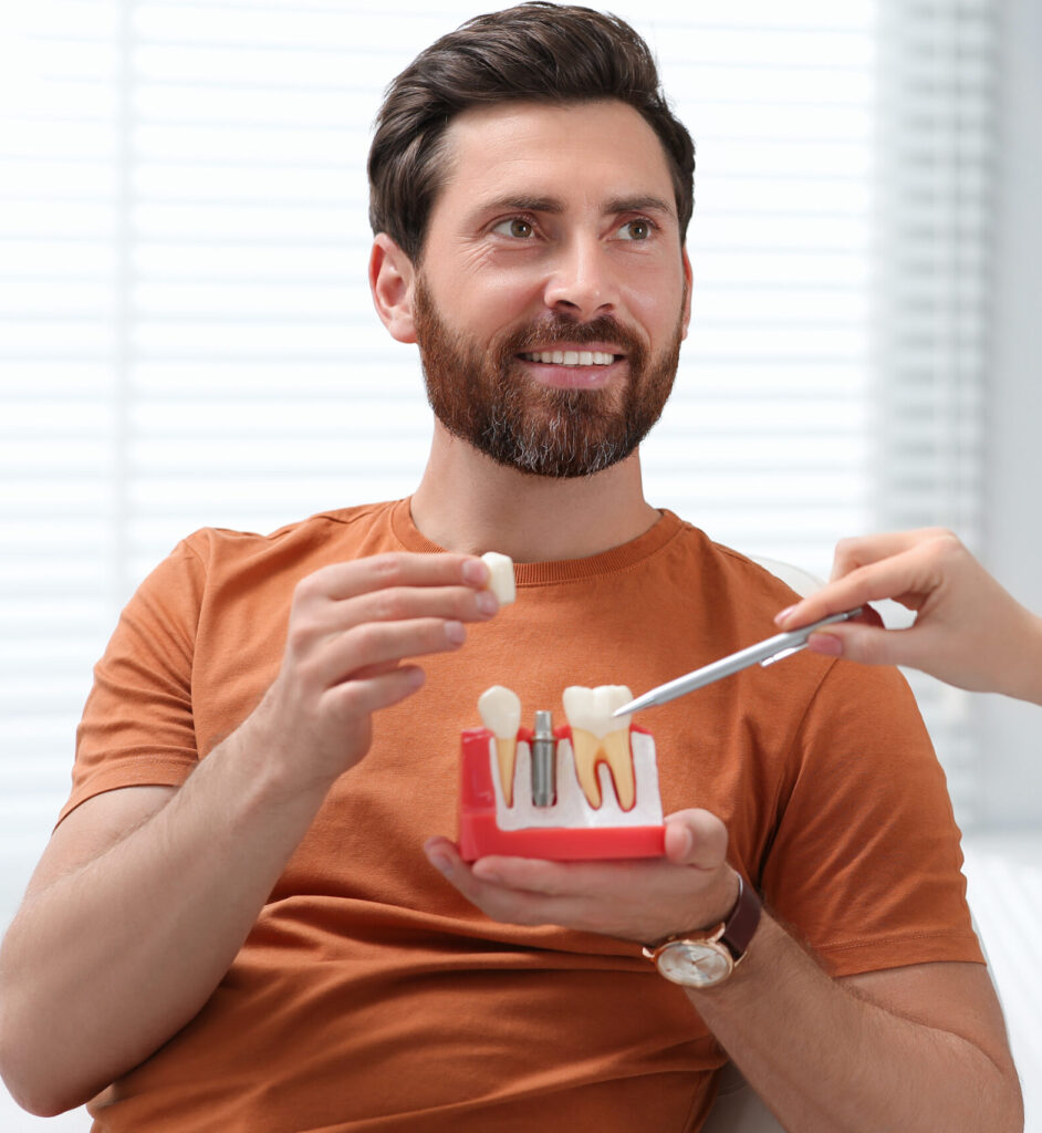 Doctor with educational model of dental implant consulting patient in clinic