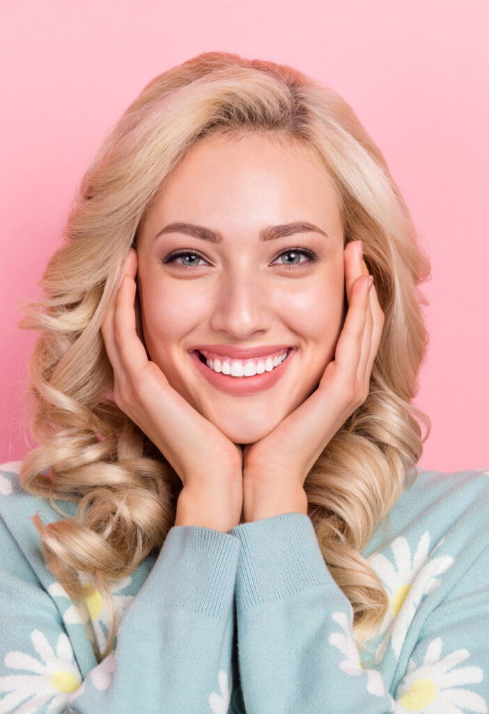 Portrait of cute lady wear blue shirt daisy flowers print touch cheeks enjoy stomatology salon veneers isolated on pink color background.