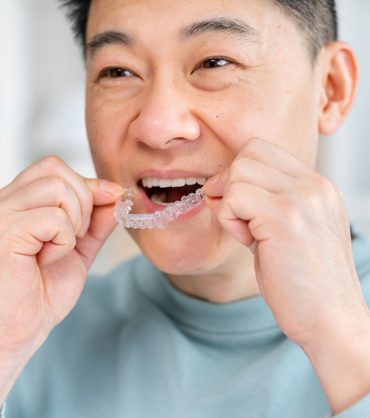 Close-up of man wearing orthodontic silicone trainer. Invisible braces aligner.